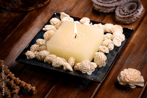 Aromatic rustic candle with white sola flowers on wodden table photo