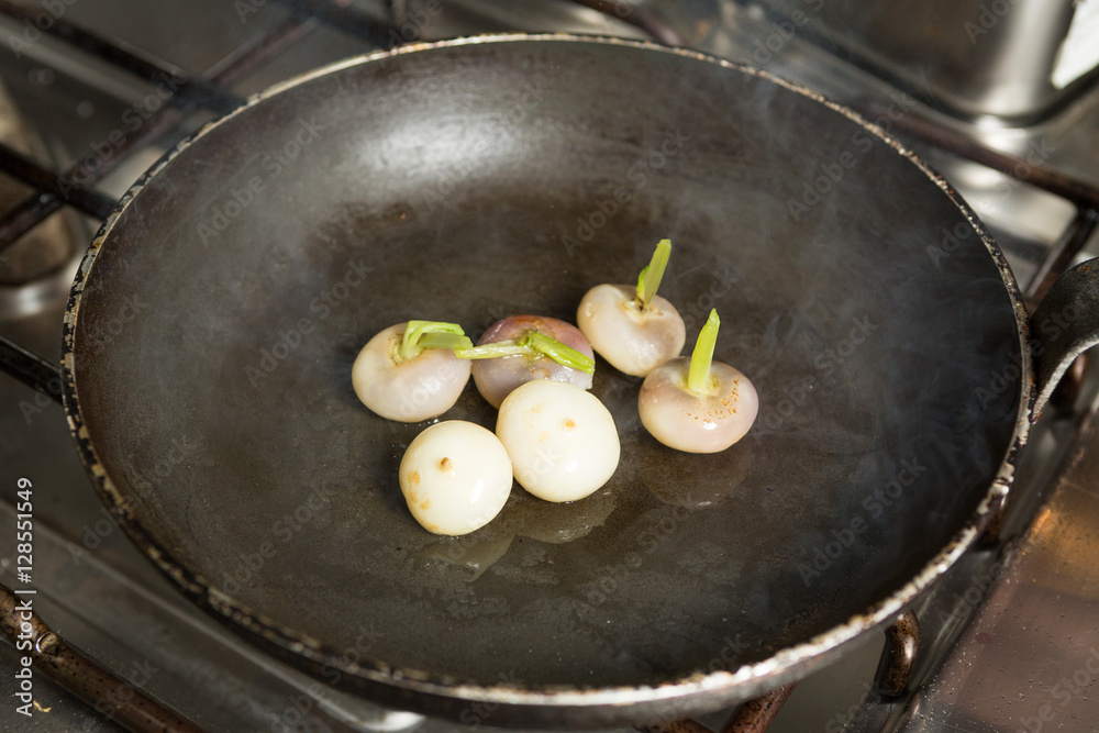 Fresh organic baby turnips, in a metal frying pan, being cooked and caramelised in a sauce. Fresh organic baby turnips, in a metal frying pan, being cooked and caramelised in a sauce.