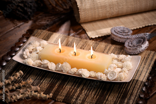 Aromatic rustic candle with white sola flowers on wodden table photo