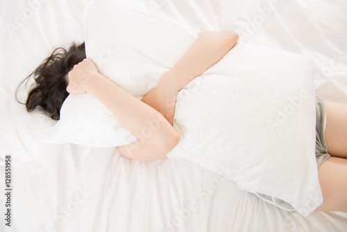 beautiful asian woman feel unwell painful and holding pillow