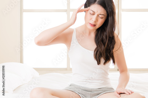 Beautiful asian woman suffering headache and massage forehead
