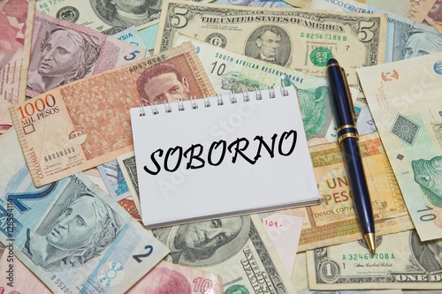 Notebook page with SPANISH text "SOBORNO" (BRIBE), background from different world Currencies