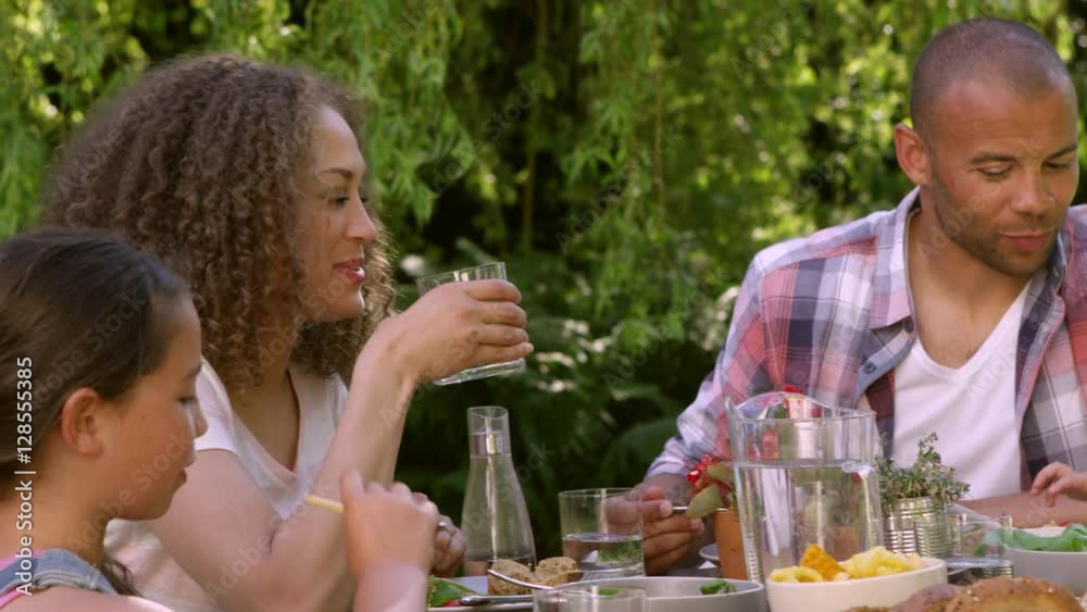 Family At Home Eating Outdoor Meal In Garden Together Family At Home Eating Outdoor Meal In Garden Together