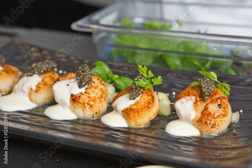 Photography Delicious pan seared organic scallops, served with celery puree, caviar, parsley and white wine cream sauce