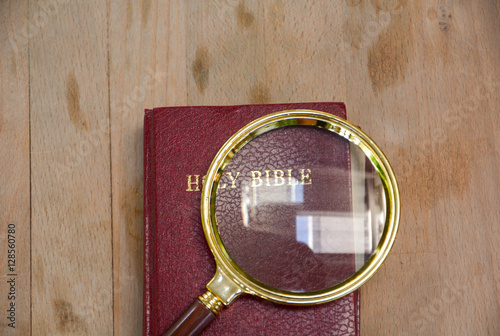 bible book and magnifying glass on wood background