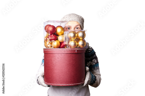 Young cute smiling girl in sweater, holding a box of Christmas decorations. Winter, Cristmastime, New Year holiday. photo