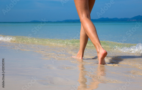 Woman walking on sand beach leaving footprints in the sand