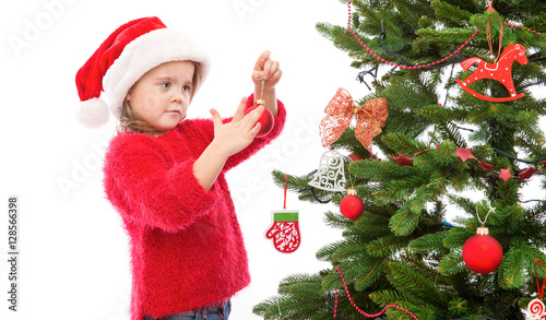 Little girl hanging Christmas decoration on the tree