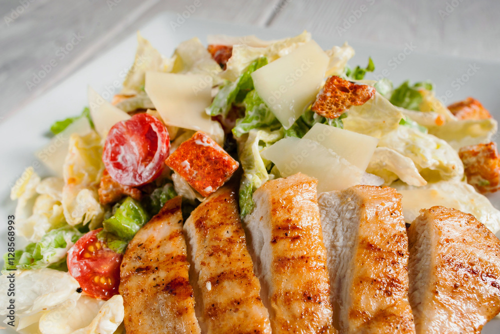 Fried chicken strips with fresh vegetable salad close-up. Served caesar on white plate. Mediterranean cuisine, restaurant menu, appetizing concept Fried chicken strips with fresh vegetable salad close-up. Served caesar on white plate. Mediterranean cuisine, restaurant menu, appetizing concept