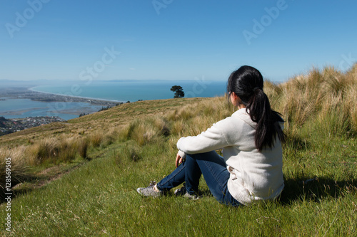 Girl sits on hill top and looks at city below