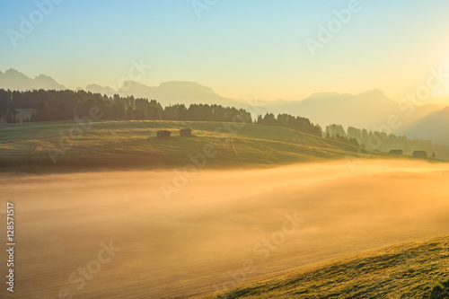 Autumn fog at sunrise over the meadow, Dolomites, Italy