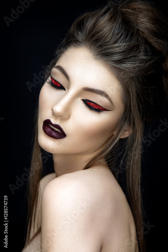 Beautiful woman portrait in asian style with red eyeshadows on black background. 
