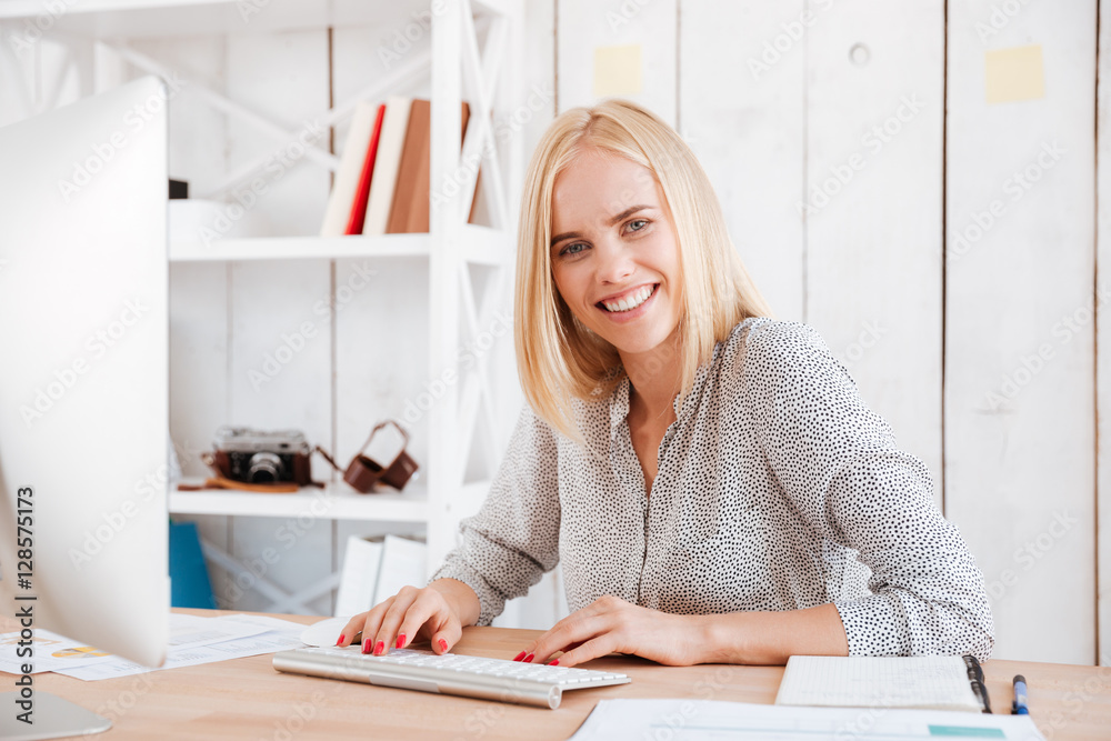 Happy young business woman sitting with computer in office