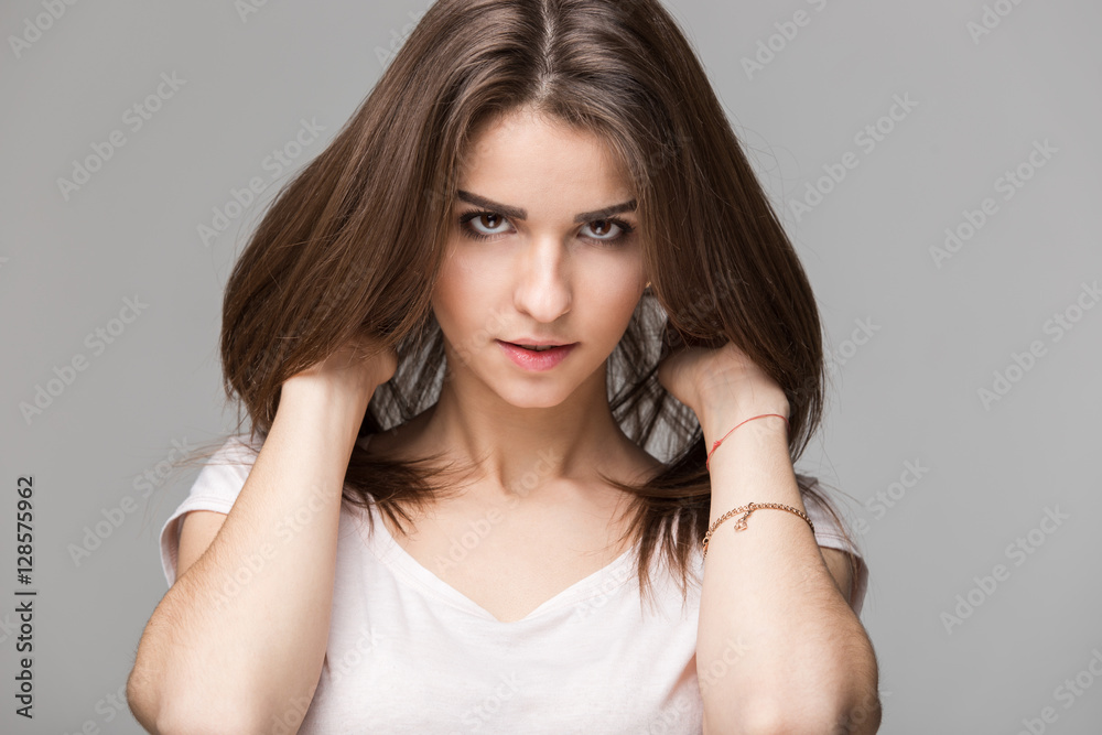 Portrait of beautiful brunette woman with natural make-up, on grey background Portrait of beautiful brunette woman with natural make-up, on grey background