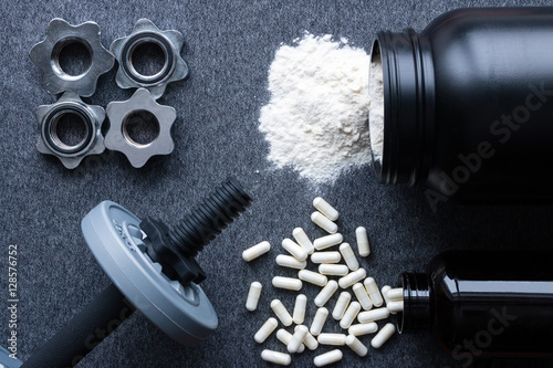 Foto dumbbells, protein and amino acids on a gray background
