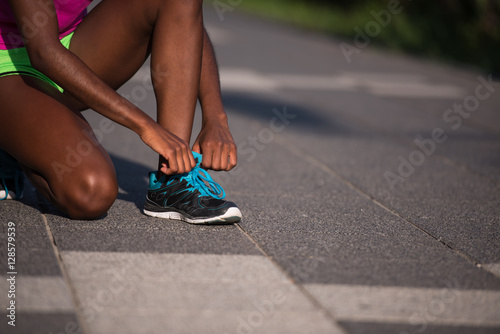 African american woman runner tightening shoe lace