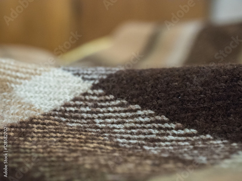 Selective focus on brown blanket texture close up. Blanket texture pattern against blurred bright background.