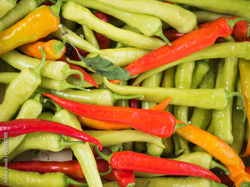 Background of a stacked colourful peppers on sale at the market. Green and red peppers close up. photo