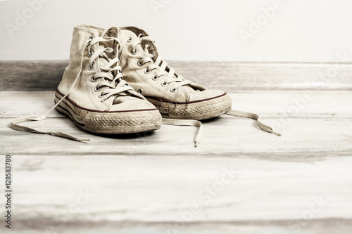 Old white sneakers on wooden background