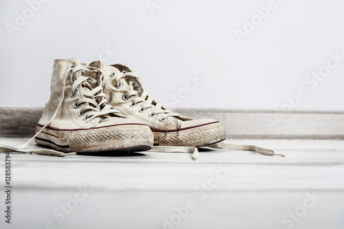 Old white sneakers on wooden background