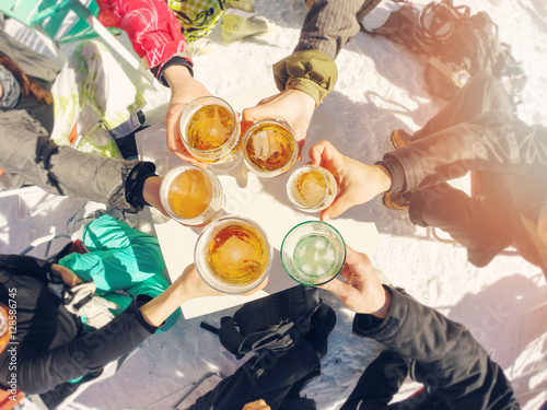 winter holidays - group of friends drinking beer on break at ski
