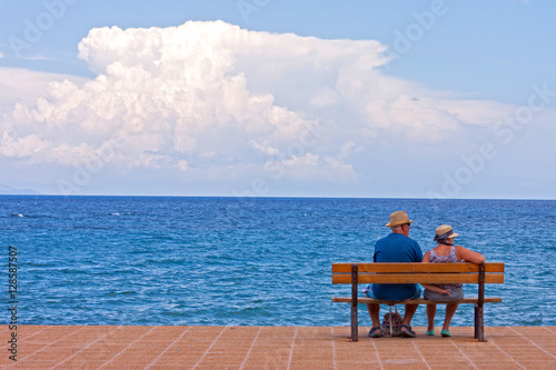 A copy of seniors sitting on a bench at sea shore © xiaoma