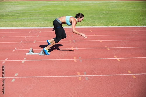 Female athlete running from starting blocks