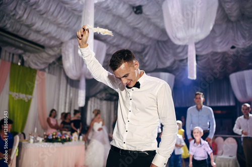 Cute groom is holding a  garter of his bride