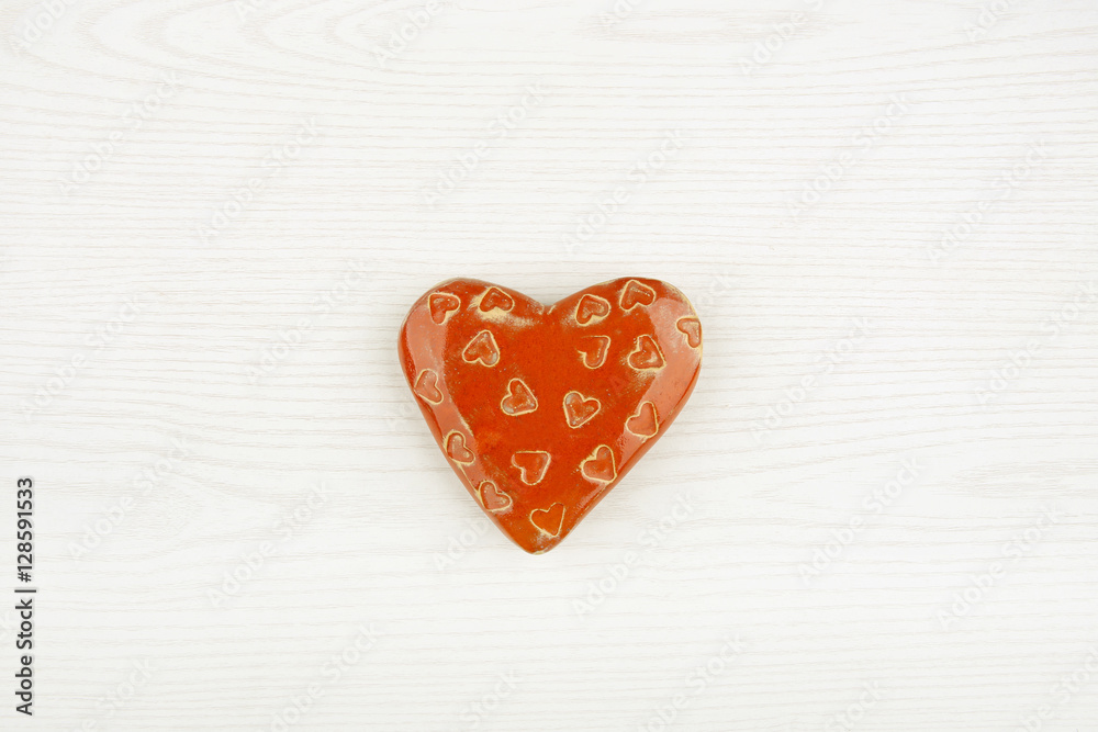 Ceramic heart isolated on white wooden background. Decorative red heart top view.