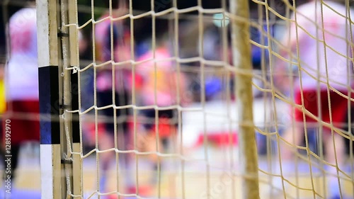 Handball match scene with goalpost net and players in the background
