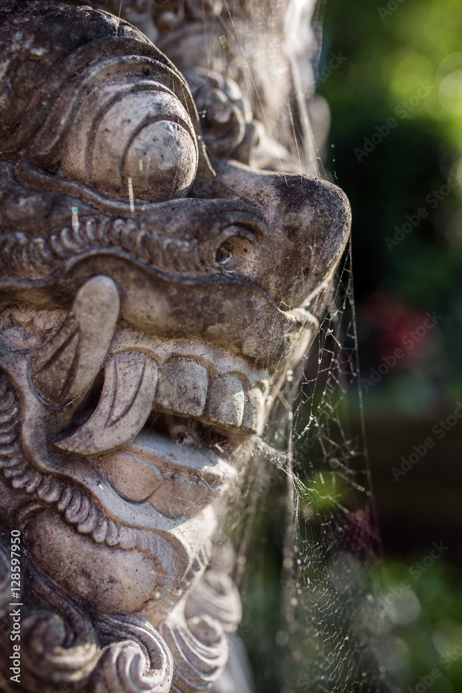 Traditional guard demon statue carved in dark stone on Bali island