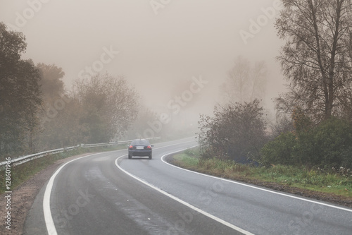 Foggy road, car goes on empty highway