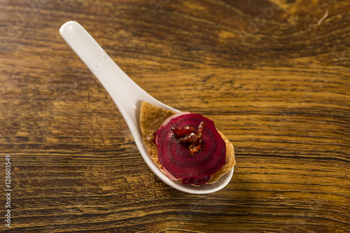thousand leaves of radish and beet with caramelized bacon julienne in a spoon. Taste gastronomy finger food
