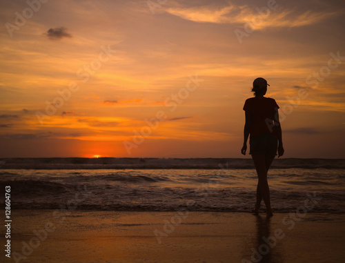 Young beautiful slim girl on the beach watching the sunset and the horizon. Sea sunset landscape