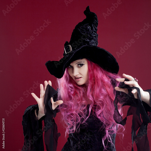 Attractive woman in witches hat and costume with red hair. Halloween