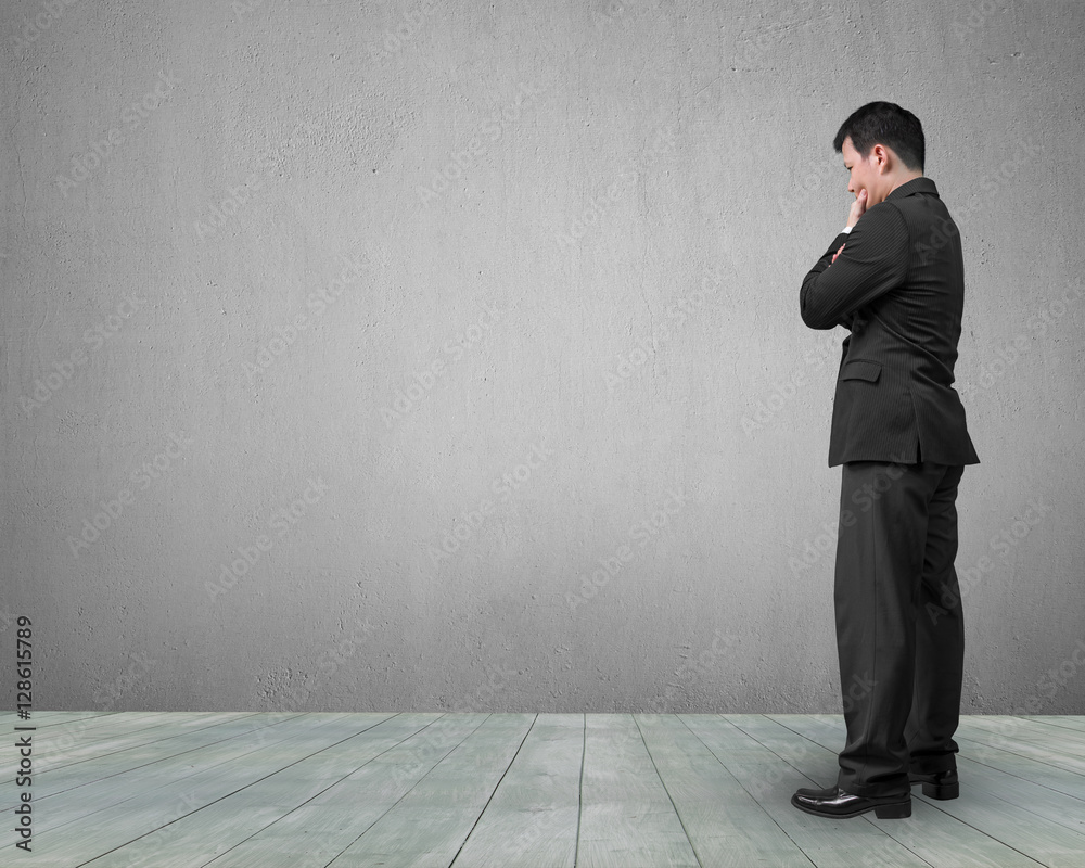 Standing businessman holding hand on chin and thinking Standing businessman holding hand on chin and thinking