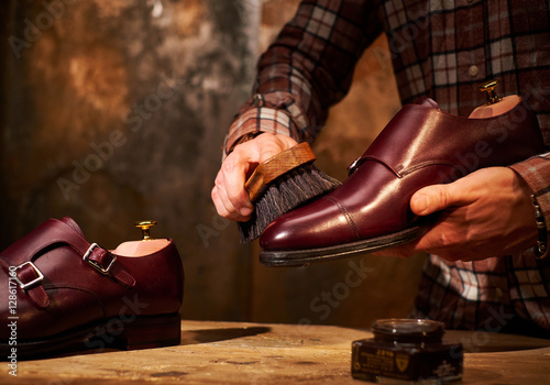 Obraz na plátne Man polishing leather shoes with brush