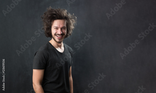 Portrait of a fashionable young man with funny hair on dark back