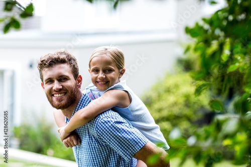 Smiling father carrying daughter in yard 