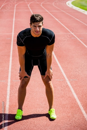 Tired athlete standing on running track