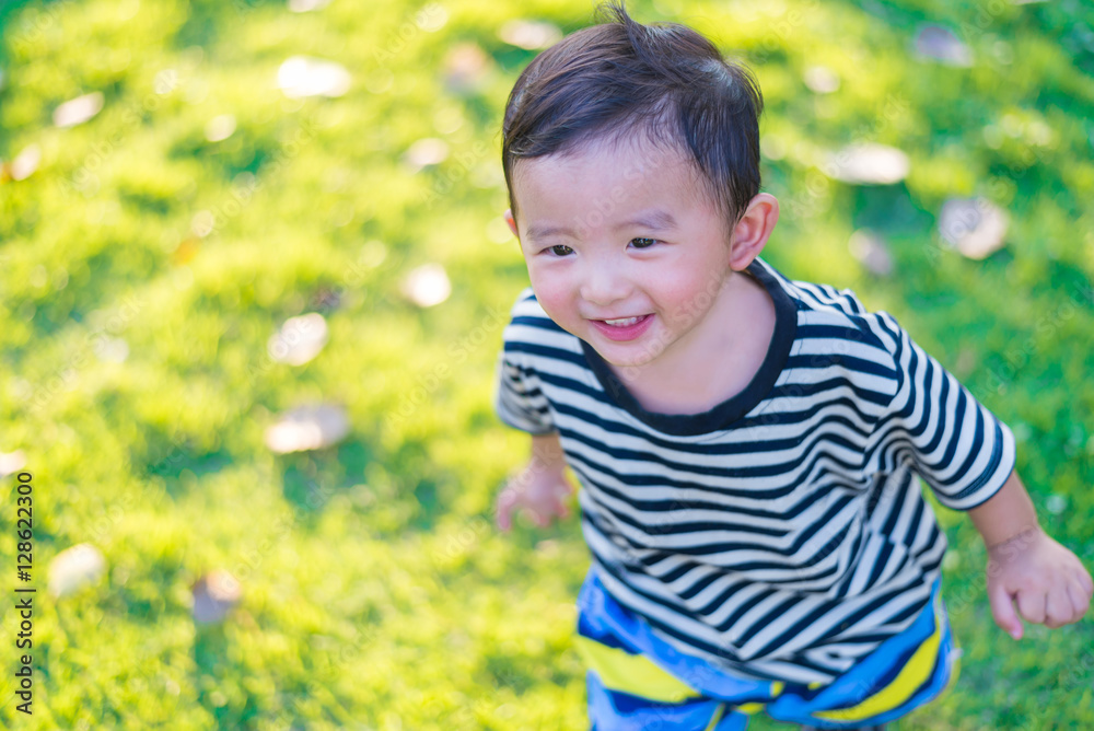Little Asian kid playing and smiling at the playground under the Little Asian kid playing and smiling at the playground under the