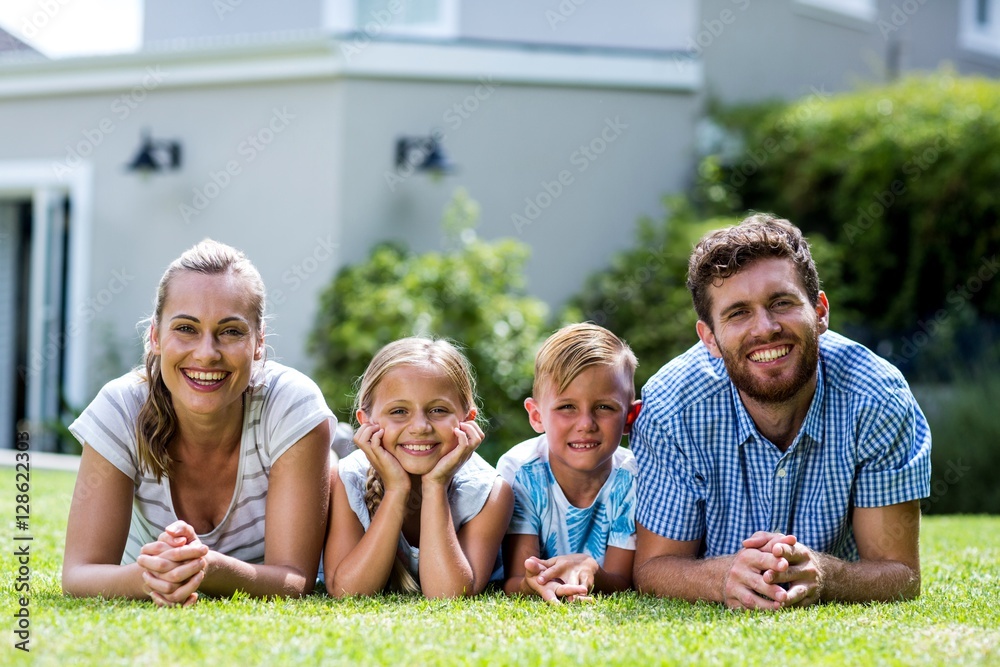 Front view of happy family lying in yard 