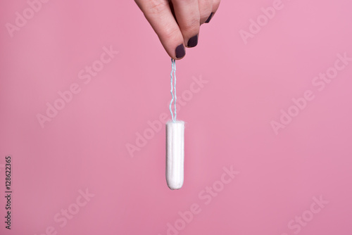 Woman's hand holding a clean cotton tampon photo