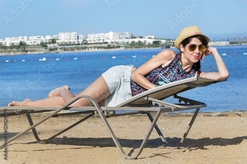 beautiful fashion woman with straw hat relaxing on the beach.Summer holiday concept