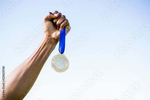 Athletes hand holding gold medal after victory