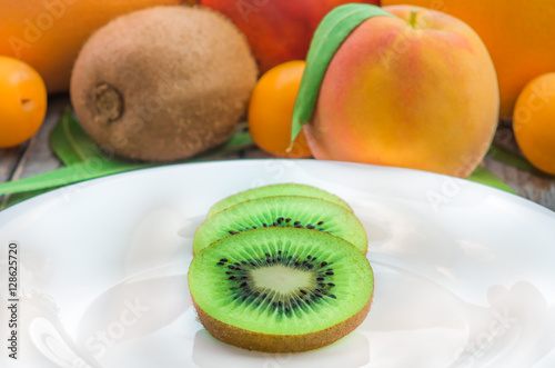 sliced kiwi on a white plate and other fruits
