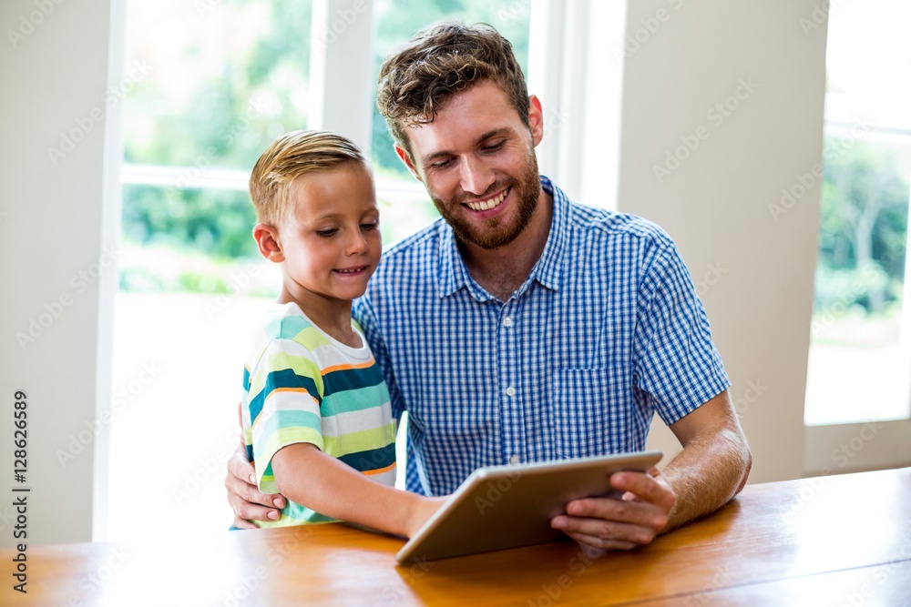 Father and son looking into digital tablet at home Father and son looking into digital tablet at home