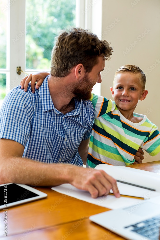 Smiling father teaching son at home Smiling father teaching son at home