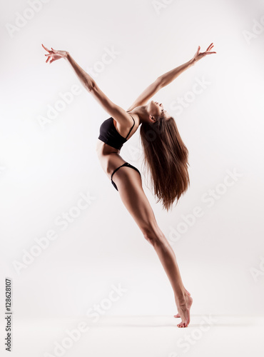 Acrobatic dancing woman posing on light background