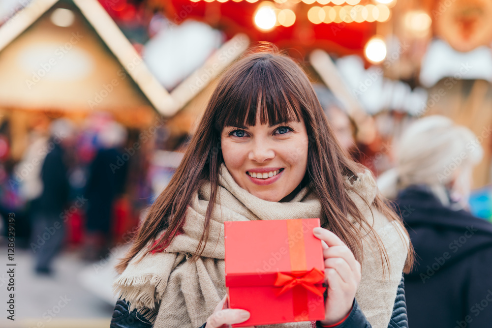 beautiful woman holding a present box on a christmas market beautiful woman holding a present box on a christmas market